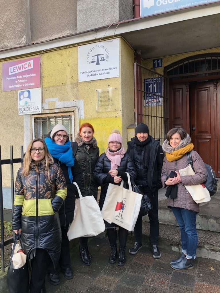 The team stands in front of the building of the Immigrant Support Center in Gdańsk.
